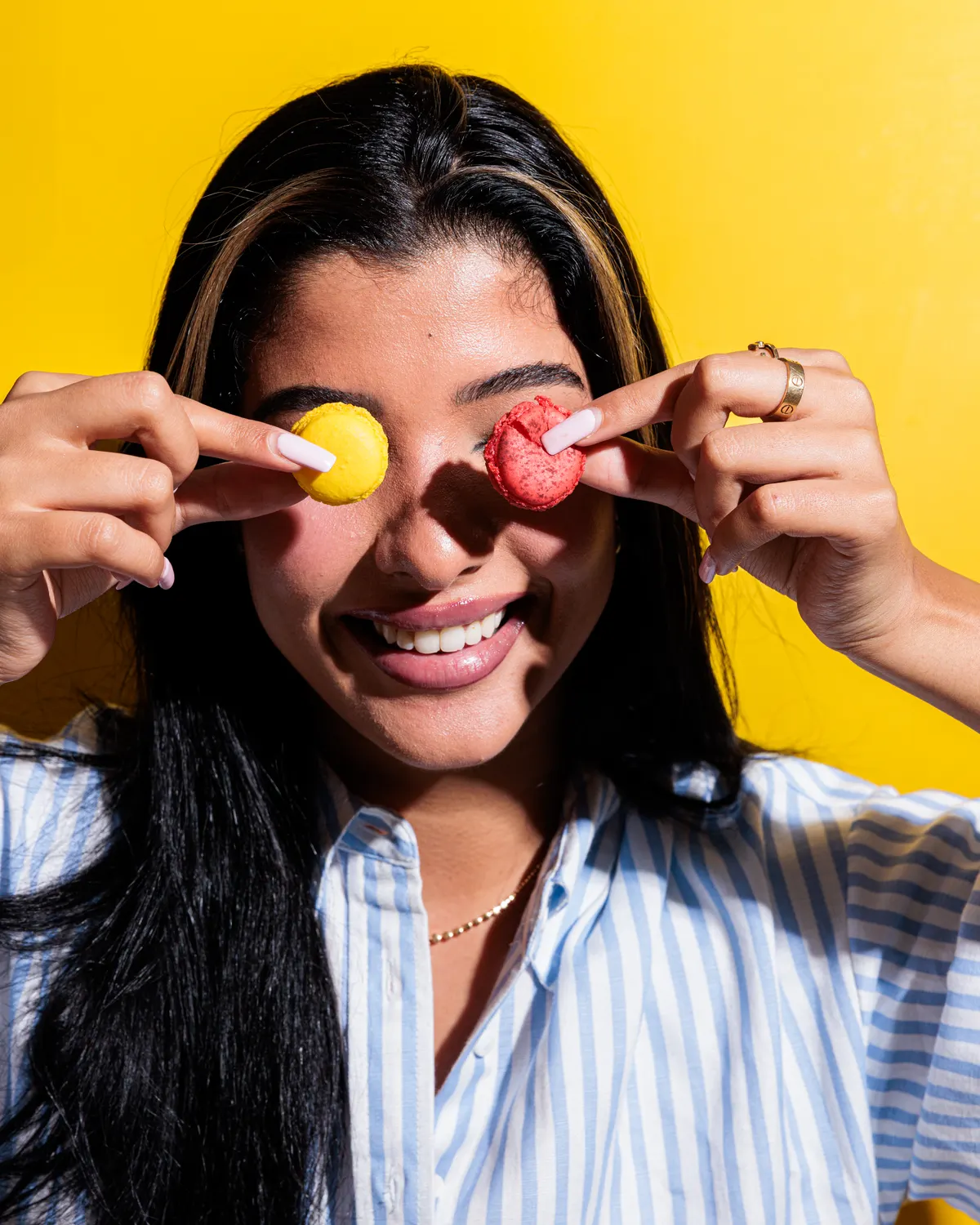 A laughing guest holding two macarons over her eyes